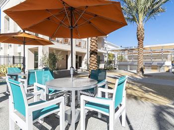 A table with chairs and umbrellas is set up outside.